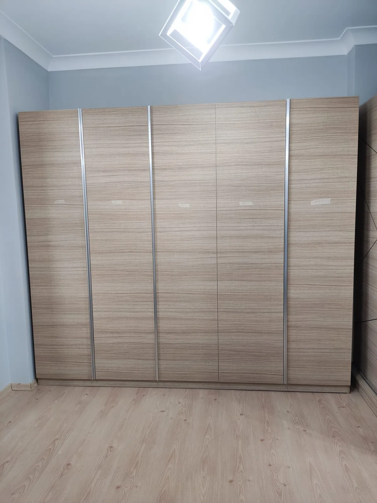 Ahşap desenli kapakları ve dikey profilleriyle geniş gardırop