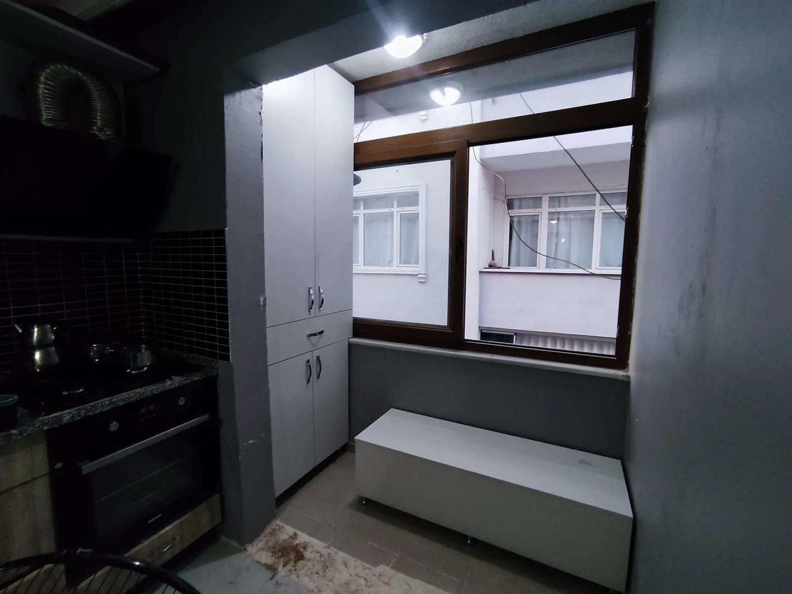 Pencere çevresinde camlı üst modüller ve oturma bankıyla balkon dolabı
