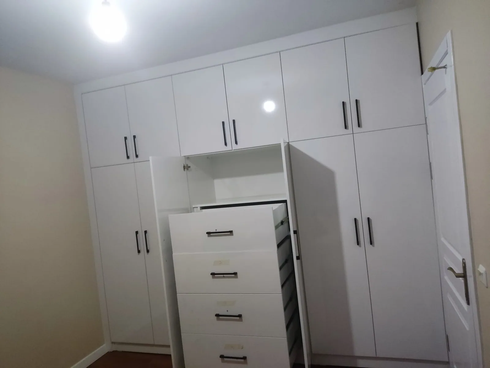 Çekmeceli merkez bölüm, raflar ve askı alanlarıyla açık beyaz gardırop