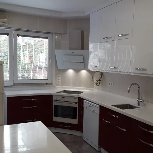 Beyaz üst ve bordo alt dolaplarla L biçimli mutfak