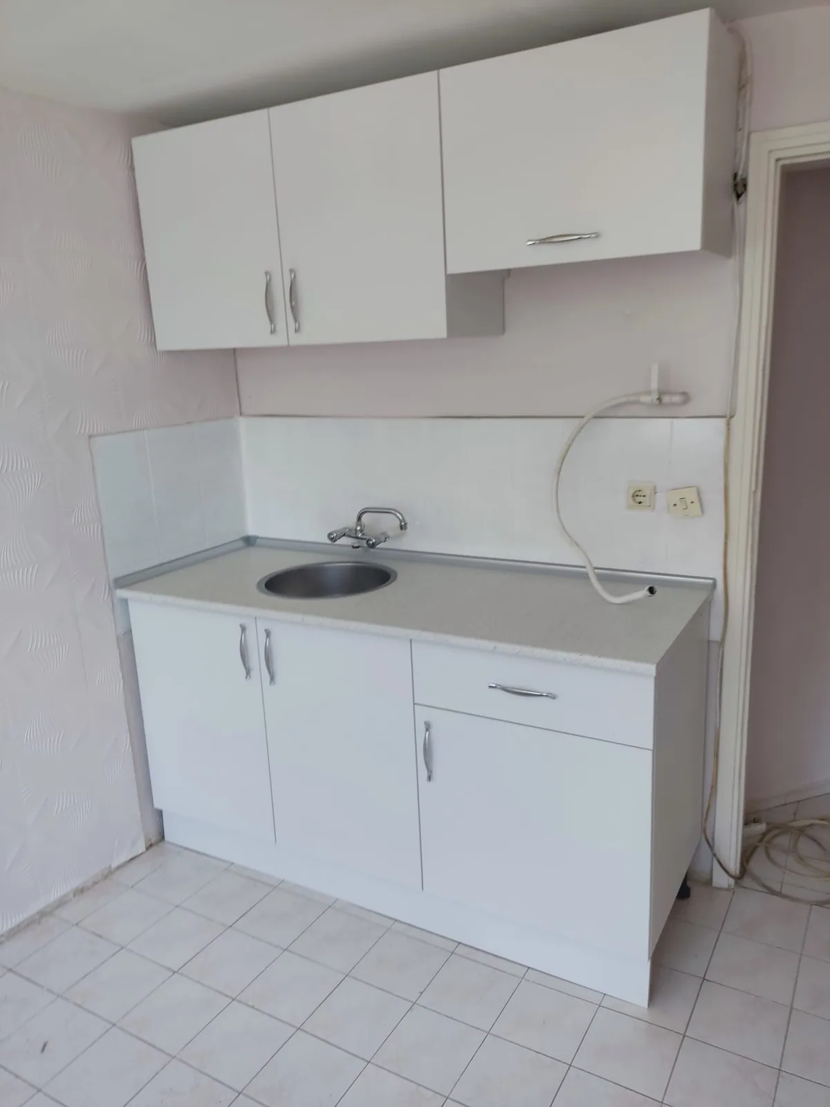 Lavabo, beyaz alt dolaplar ve üst modüllerle kompakt mini mutfak