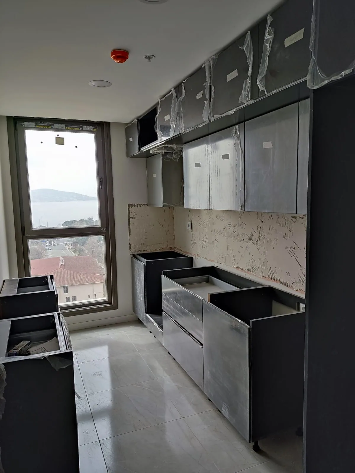 Koyu kapaklı alt üst dolapları ve pencere önü tezgâhıyla mutfak