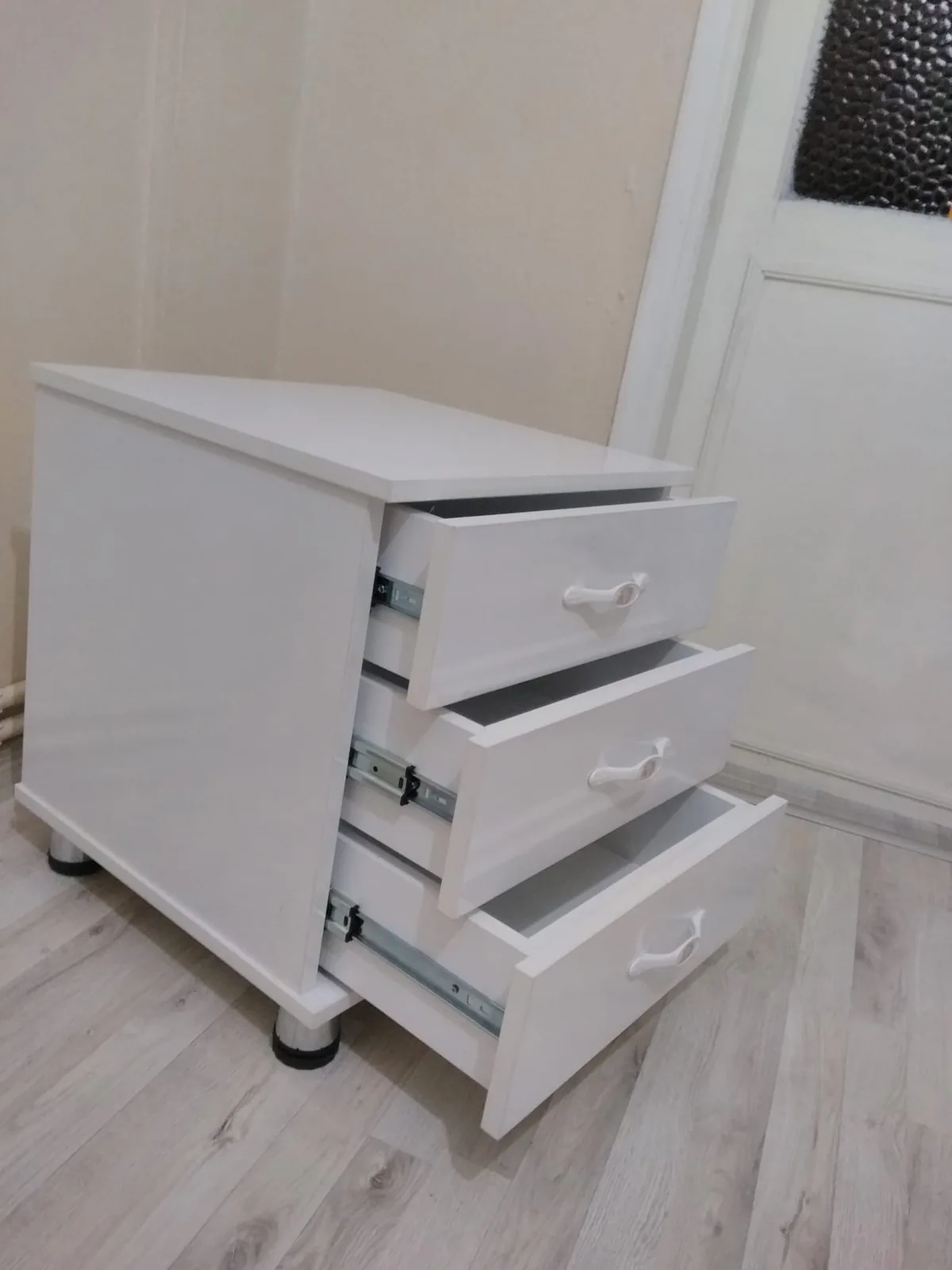 Tekerlekli beyaz komodinlerin ön ve yan görünümü
